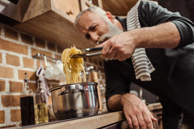 Mann kocht Spaghetti