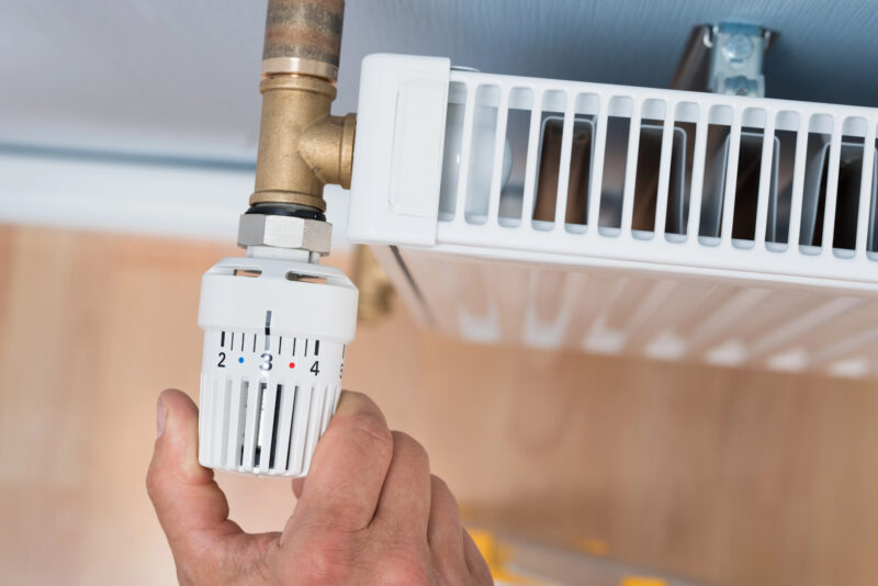 Mann dreht an Heizungsthermostat