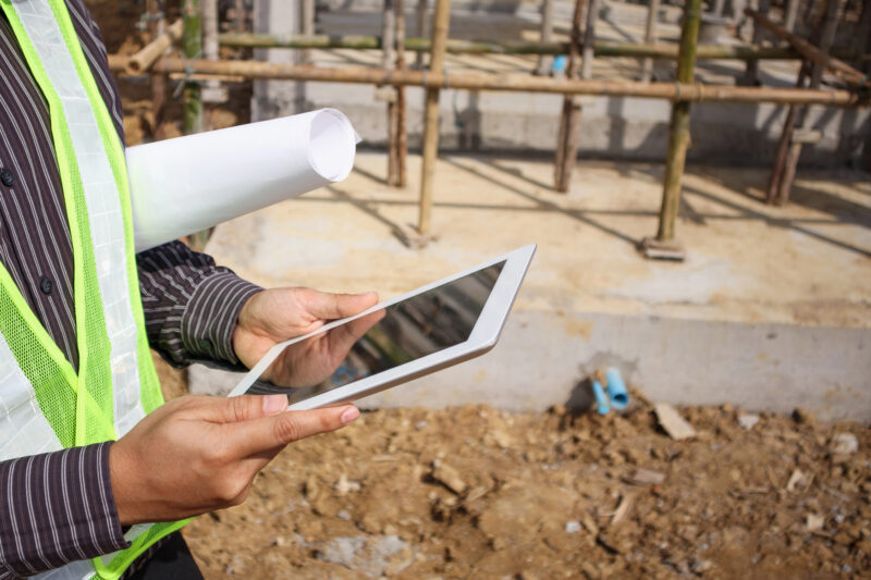 Mann hält Tablet auf der Baustelle in der Hand