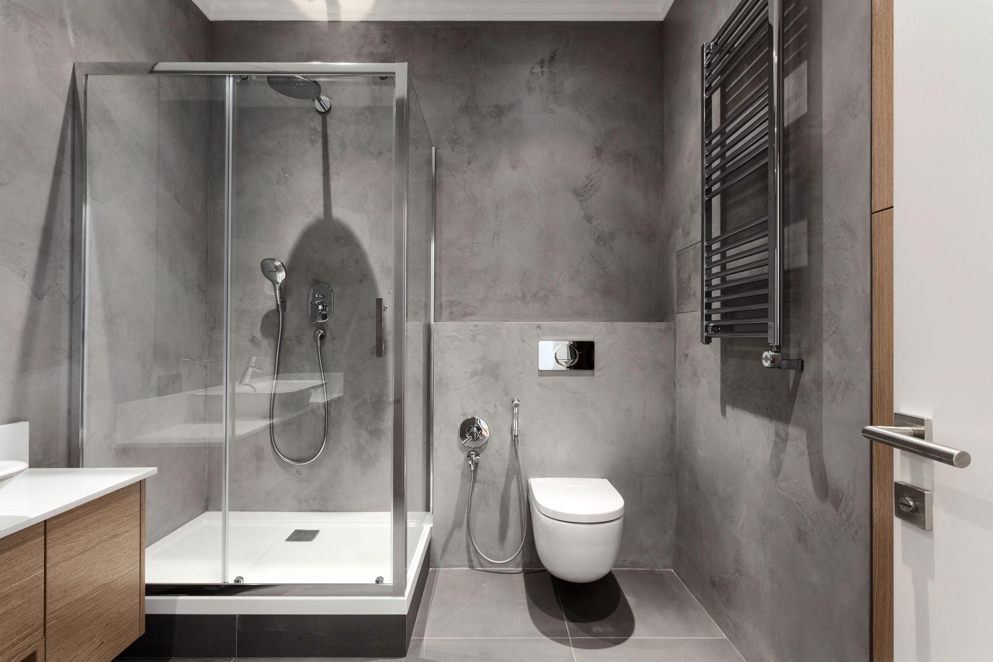 Moderne gerahmte Duschkabine aus Glas mit Schiebet&uuml;r, Duschwanne und Armaturen in einem grauen Badezimmer.